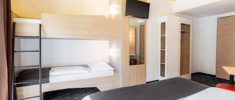 A hotel room with a bunk bed, a desk with a chair, a wardrobe, and a television.