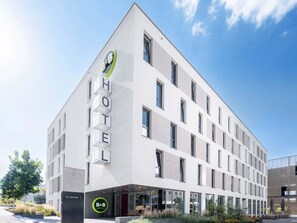 A modern hotel building with a prominent 'HOTEL' sign on the facade, a B&B logo, and a clear sky in the background. - B&B Hotel Stuttgart-Zuffenhausen (Stuttgart)