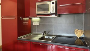 A kitchen with red cabinets, a stainless steel sink, and an LG microwave. - Ski-In/Ski-Out Apartment, 6 Guests, Terrace & Private Ensuite (Montgenèvre)