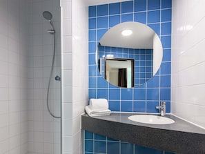 A bathroom with a shower, a sink, and a mirror. - B&B Hotel Landshut (Landshut)