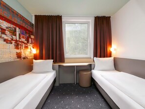 A small, compact room with two single beds, a small desk, and a window with curtains. - B&B Hotel Berlin-Dreilinden (Kleinmachnow)