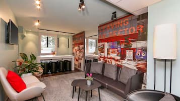A modern living room with a sofa, armchairs, a coffee table, and a TV mounted on the wall.