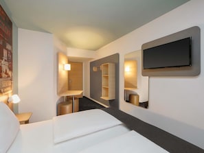 Een moderne hotelkamer met een bed, een aan de muur bevestigde televisie en een spiegel die de kamer reflecteert.