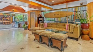 A spacious lobby with a wooden ceiling, a large sofa, a glass coffee table, and a bookshelf. - 1 BR Suite City View, w/ AC, WiFi and Kitchen - Bamboo Waikīkī Hotel #504 (Honolulu)