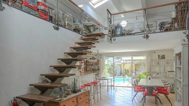 A spacious room with a unique staircase, a dining area, and a view of a swimming pool. - Beautiful house, carefully decorated by an antiques dealer, very quiet. (Aix-en-Provence)