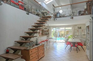 A spacious room with a unique staircase, a dining area, and a view of a swimming pool.