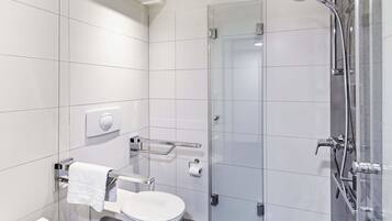 Ein modernes Badezimmer mit einer gläsernen Duschkabine, einer Toilette mit Handtuchhalter und einem Handtrockner.