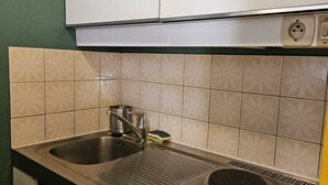 Une cuisine équipée d’un évier à deux bacs, d’un robinet en acier inoxydable et d’une cuisinière intégrée.