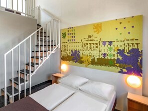 A hotel room with a bed, a white staircase, and a colorful wall mural. - B&B Hotel Braunschweig-Nord (Braunschweig)
