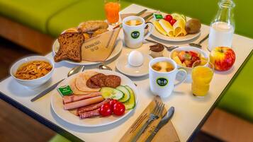 A breakfast tray with various foods, drinks, and utensils.