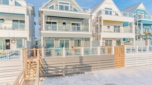 A beachfront hotel with multiple balconies, a pool, and a wooden deck. - Sea Turtle - Luxury 7BR Beachfront Retreat, Private Pool, 5 Star Reviews! (Panama City Beach)