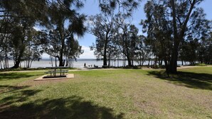 Ein Park mit Picknicktischen, einer Rasenfläche und Bäumen.