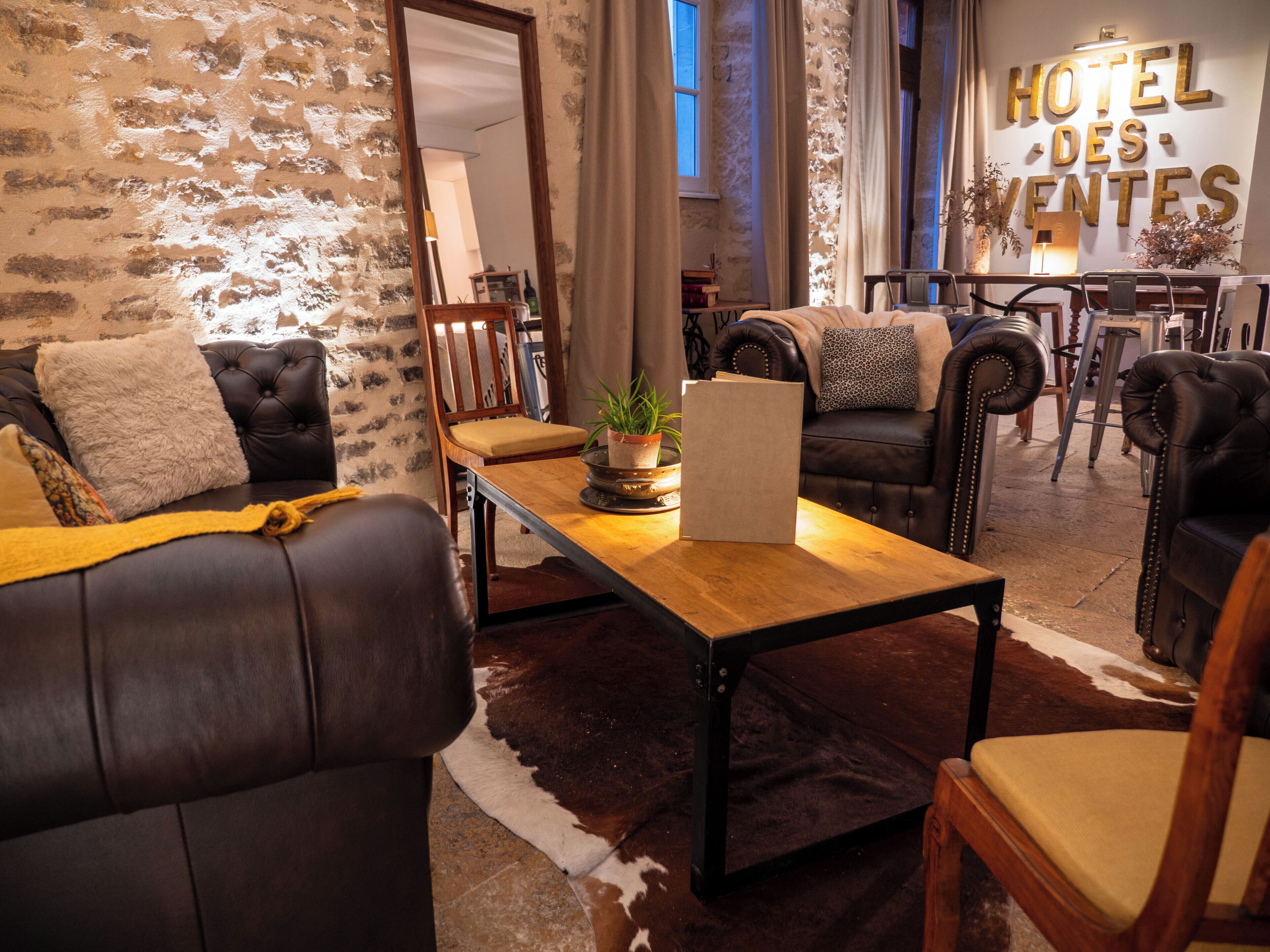 A cozy hotel lobby with leather sofas, a wooden coffee table, and a stone wall.