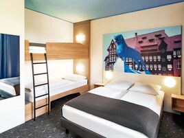 A hotel room with a bunk bed, a desk, and a painting of a horse and buildings.