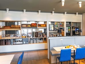 A modern breakfast area with a buffet setup, including various food items and beverages. - B&B Hotel Braunschweig-City (Braunschweig)