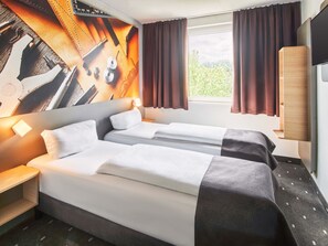 Ein Hotelzimmer mit zwei Betten, einem großen Fenster mit Vorhängen, einem an der Wand montierten Fernseher und einem Holzschrank.