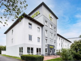 Ein modernes Hotelgebäude mit einem markanten 'HOTEL'-Schild an der Fassade, einer Rezeption und einer gepflegten Außenansicht.