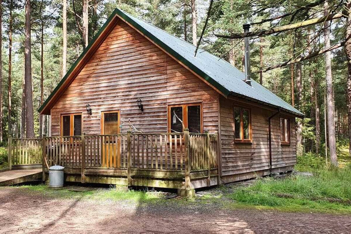 A rustic cabin with a wooden exterior, a porch, and a chimney.