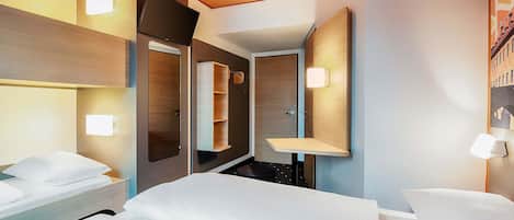 Una habitación de hotel moderna con una cama, mesitas de noche, un espejo y estanterías empotradas.