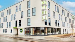 Un edificio moderno de hotel con un letrero visible que dice "HOTEL" y una zona de recepción que indica "B&B HOTELS".