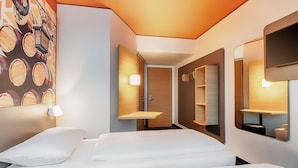 A hotel room with a bed, a wall-mounted TV, and a mirror. - B&B Hotel Bamberg (Bamberg)