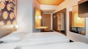 Ein Hotelzimmer mit einem Bett, einem an der Wand montierten Fernseher und einem Spiegel.