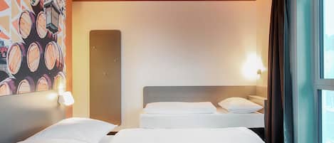 Habitación de hotel con dos camas, un ventanal con cortinas y una pared con diseño circular.