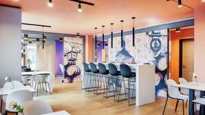 Un comedor moderno con barra, sillas blancas y un mural en la pared.