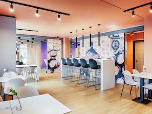 Un comedor moderno con barra, sillas blancas y un mural en la pared.