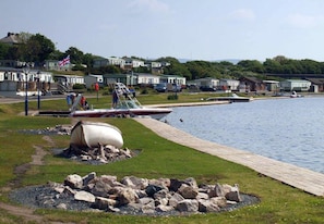 A lakeside area with a dock, a boat, and several mobile homes.