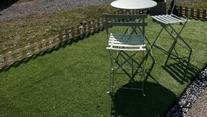 Een camping met twee stacaravans, een tafeltje en stoelen, en een grindpad.