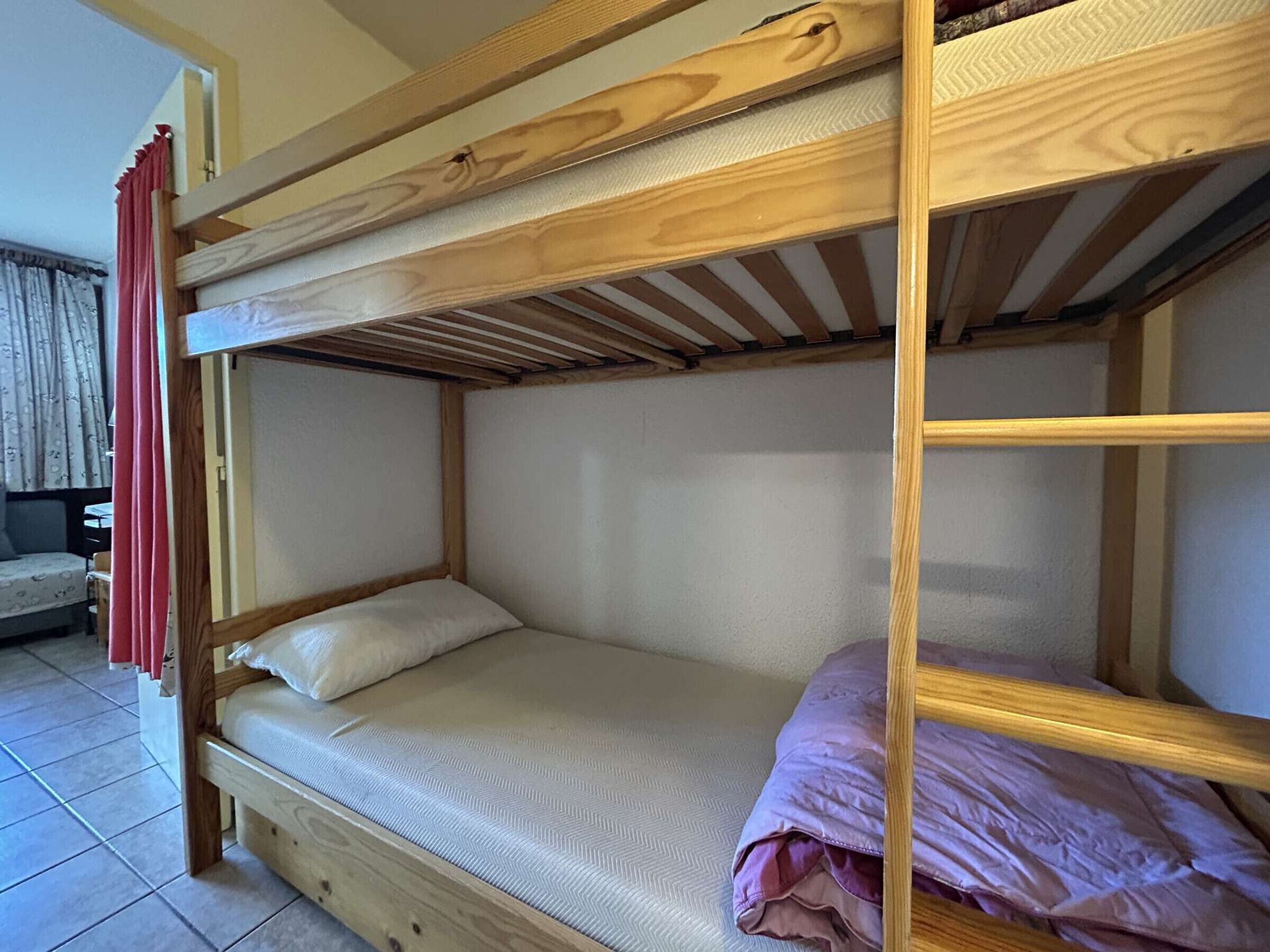 A bunk bed with a wooden frame and a mattress.