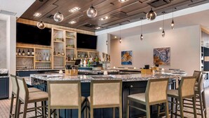 A modern kitchen with a central island, bar area, and seating. - Cambria Hotel Orlando Airport (Orlando)