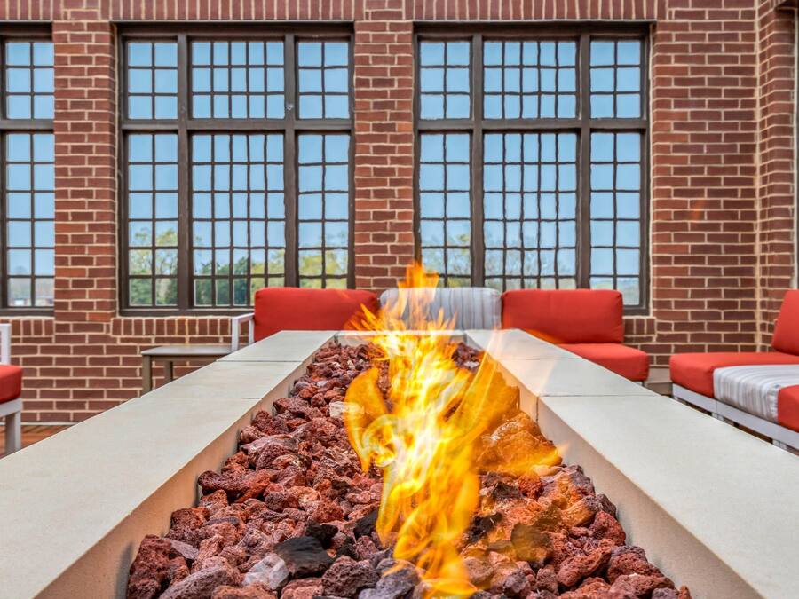 A fire feature with a brick wall and large windows in the background.