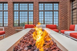 Relax by the fire pit in a cozy seating area surrounded by large windows and a brick wall.