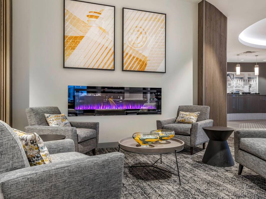A modern living room with grey sofas, a coffee table, and two framed artworks on the wall.