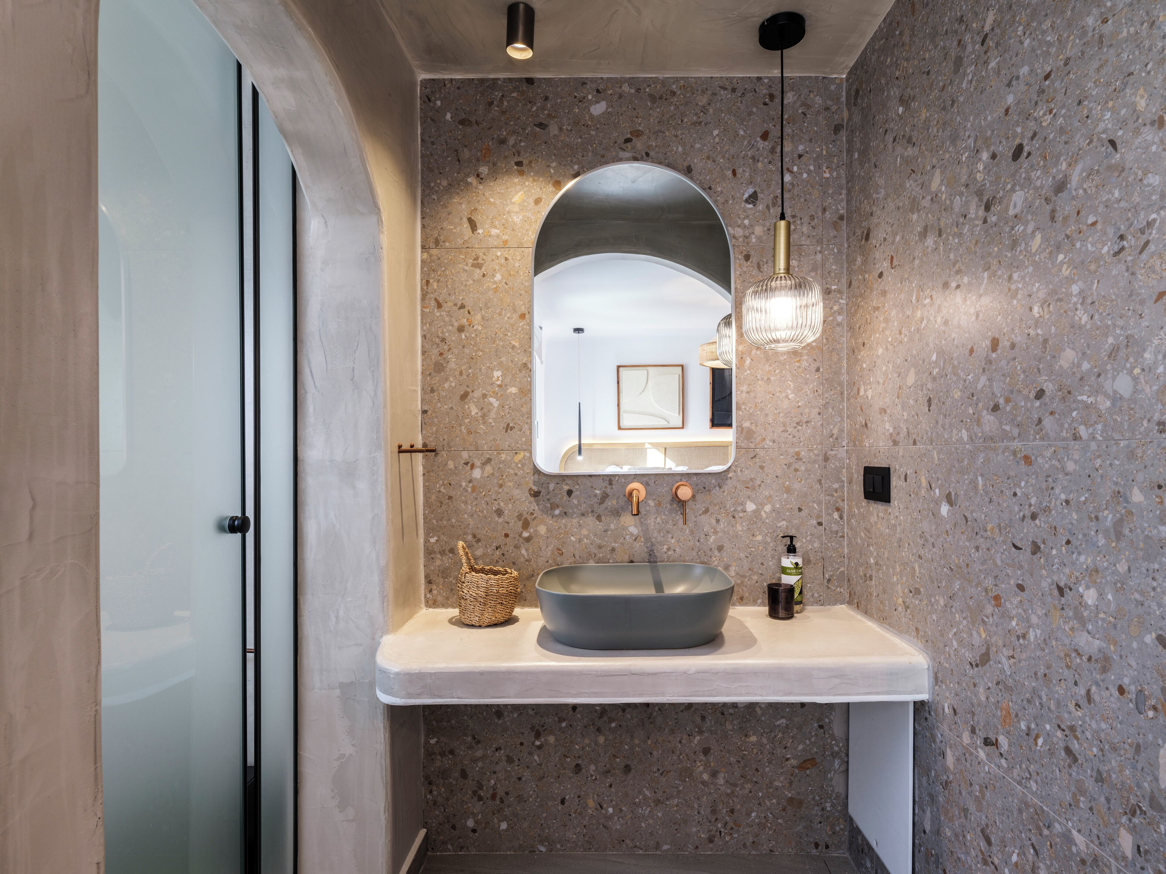 A modern bathroom with a large sink, a mirror, and a textured wall.