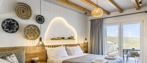 A modern hotel room with a large bed, bedside tables, a sofa, and a balcony with a view.