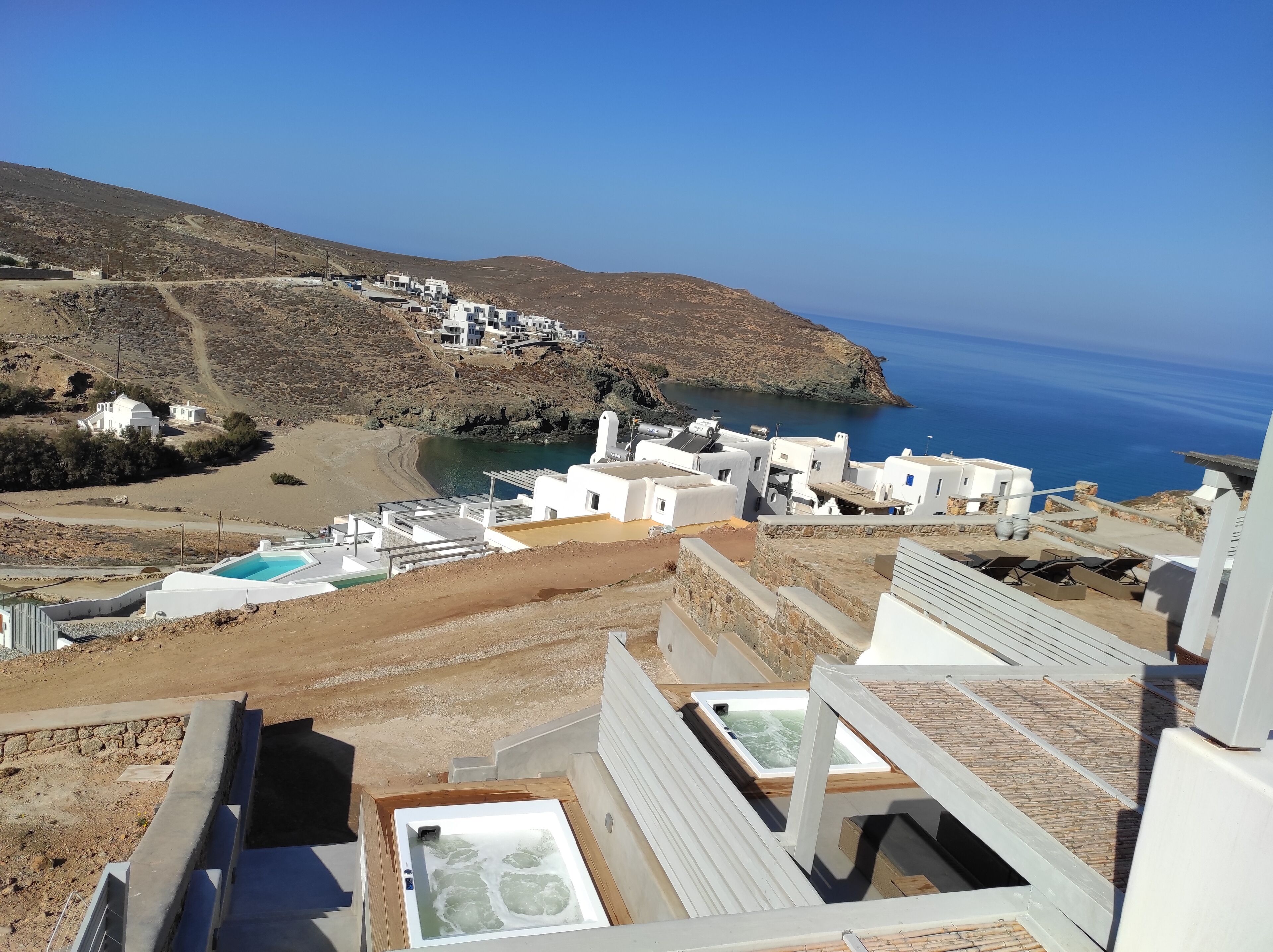 A coastal resort with white buildings, a swimming pool, and a view of the sea.