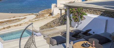 A rooftop terrace with a pool, outdoor seating, and a view of the sea.