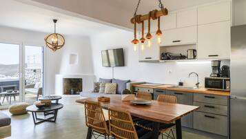 Una cocina moderna con comedor, que presenta una mesa de madera, sillas de mimbre y una lámpara colgante.