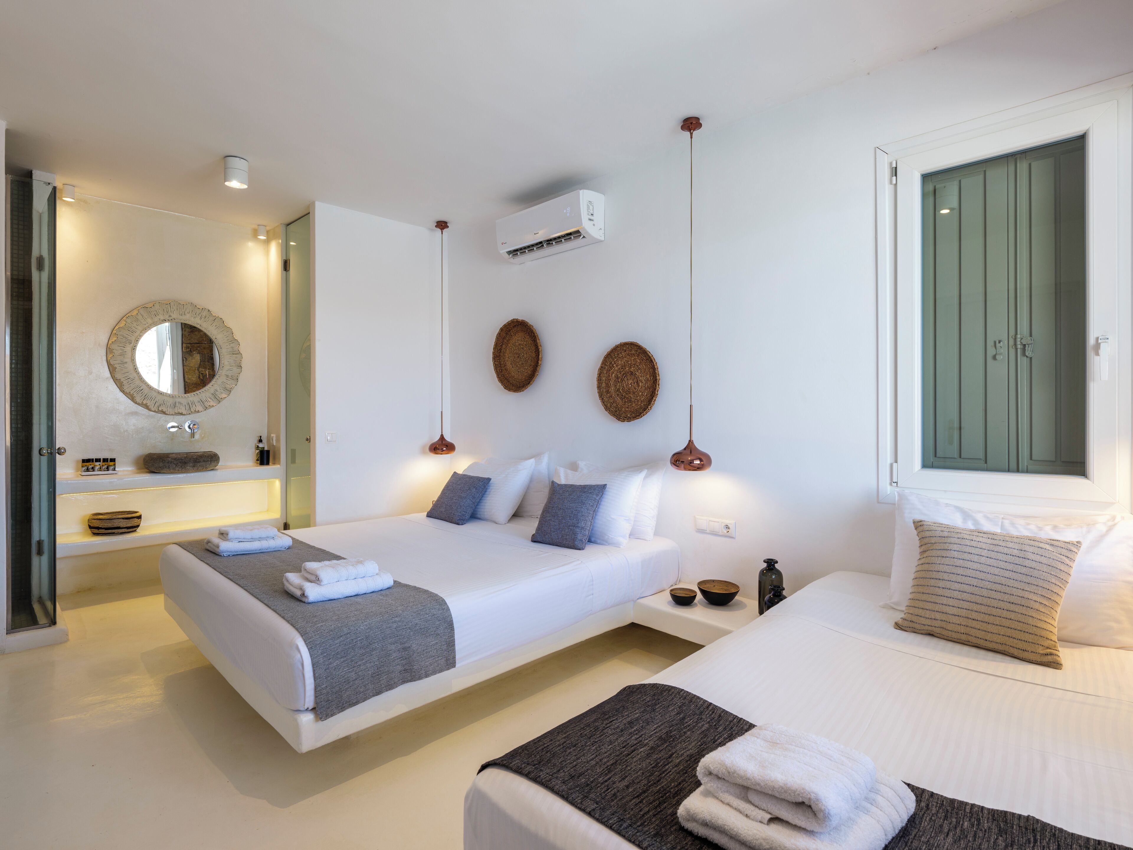 Un dormitorio moderno con dos camas, un espejo grande y una lámpara colgante.