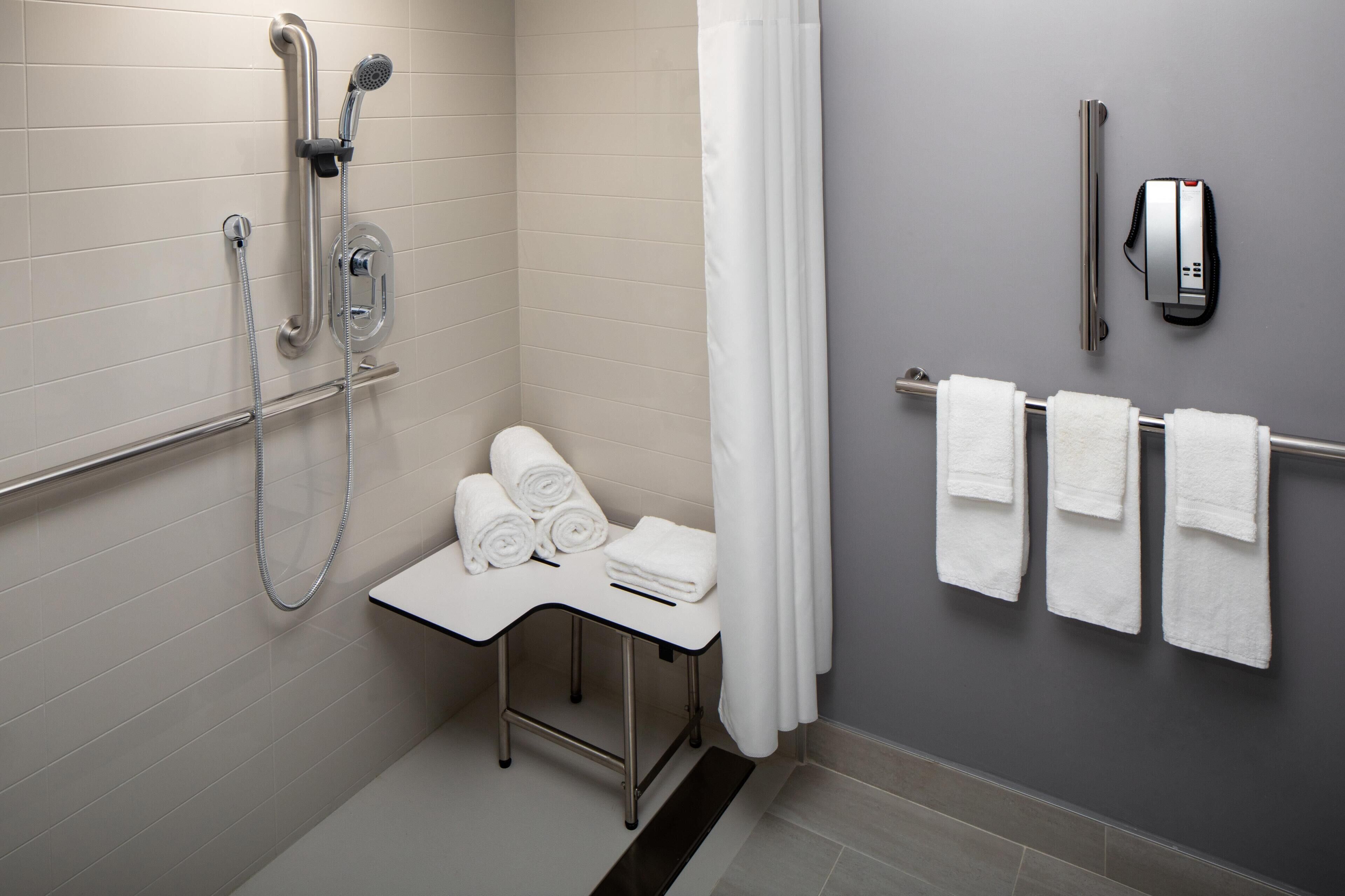 A modern bathroom with a shower, a towel rack, and a small table with towels.