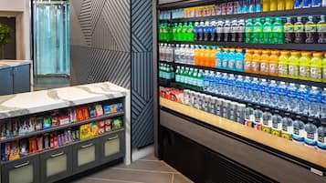 A refrigerated beverage display with various brands and a snack bar with packaged goods.
