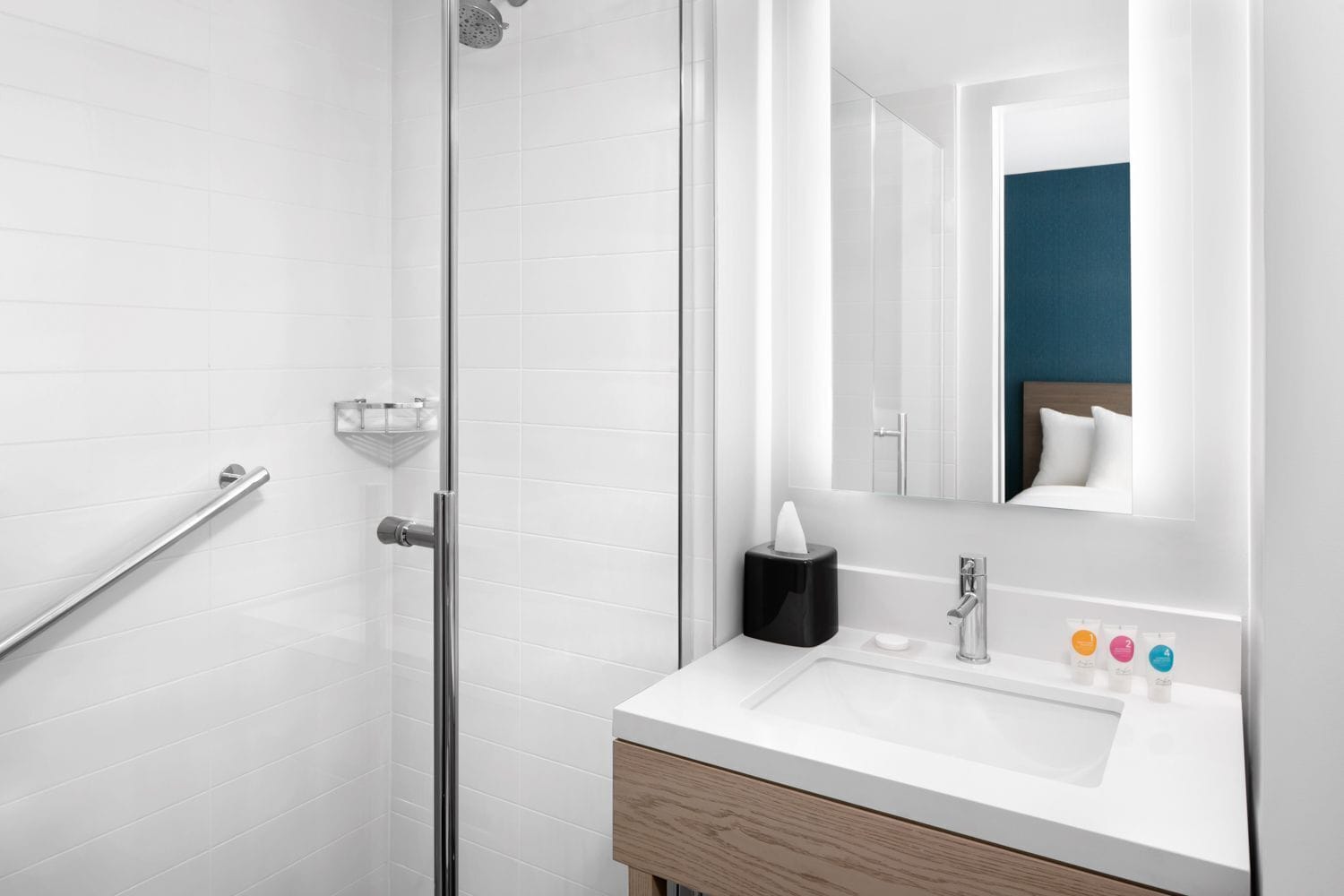 A modern bathroom with a glass shower enclosure, a white sink with a wooden cabinet, a mirror, and a towel rack.