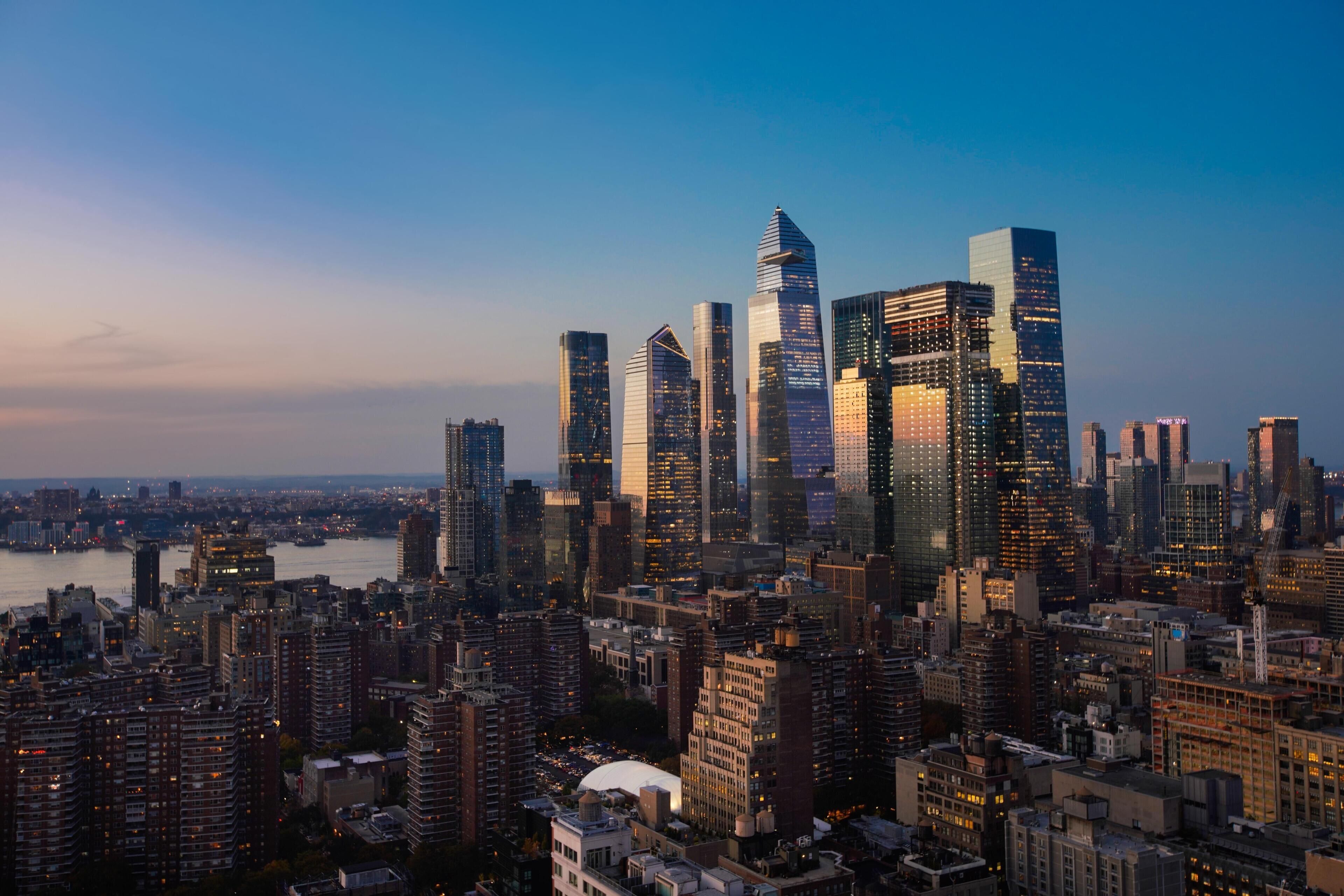 A cityscape with high-rise buildings, a river, and a clear sky.