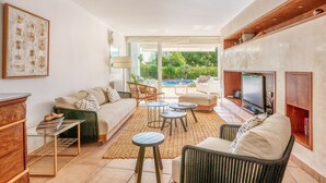 Un salon moderne avec un canapé, une table basse et un téléviseur, une cheminée et une vue sur une piscine.