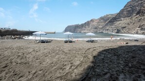 Uma praia com guarda-sóis, um penhasco rochoso e um mar calmo.