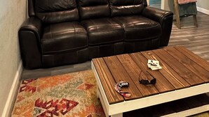 A living room with a leather sofa, a wooden coffee table, and a colorful rug. - Skip the Steep Roads! Family Cabin Hot Tub Near PF (Sevierville)