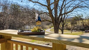 A wooden deck with a bottle of Caymus wine, a glass, and a tray of grapes. - Skip the Steep Roads! Family Cabin Hot Tub Near PF (Sevierville)